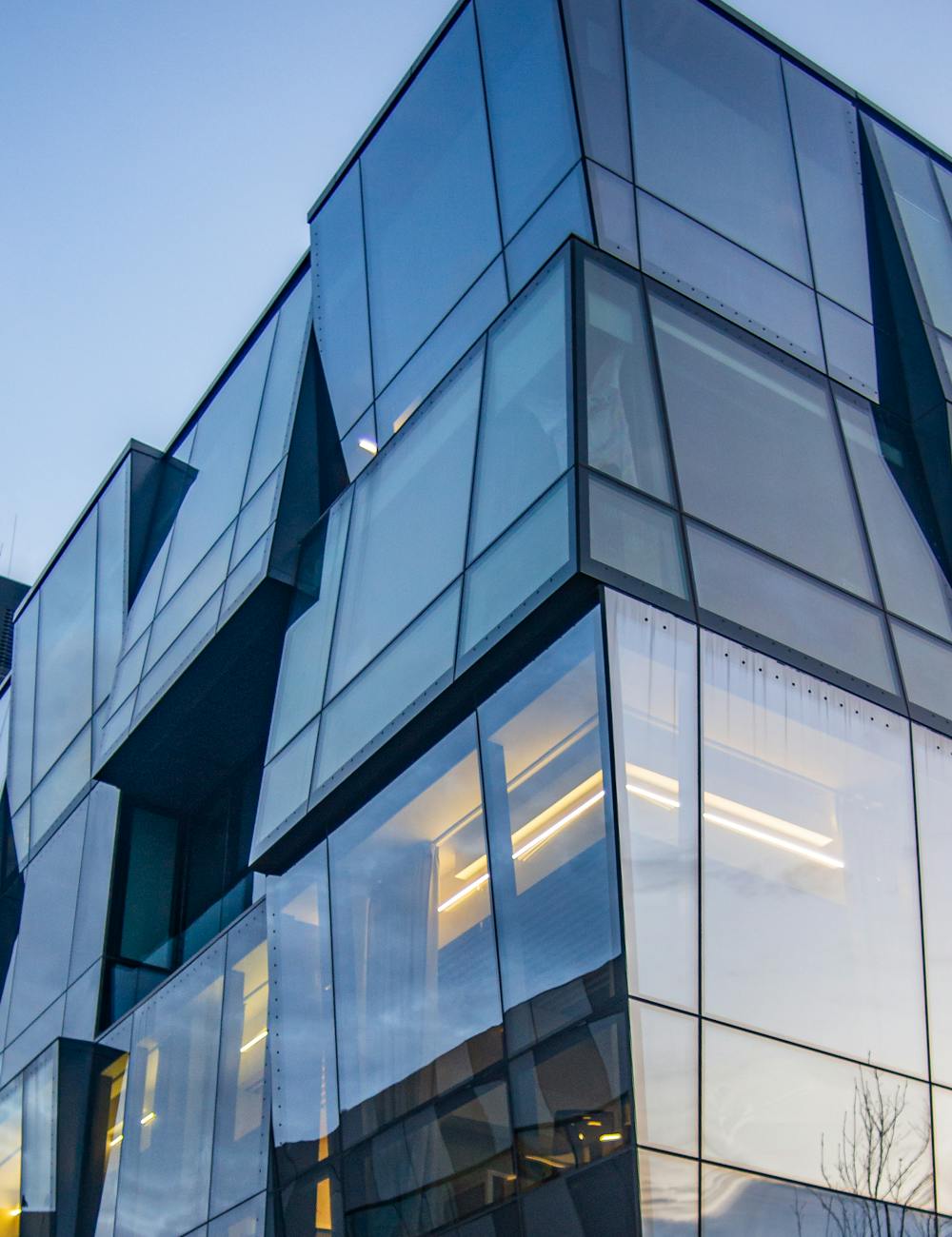 Tall modern glass-fronted building facade reflecting the city sky